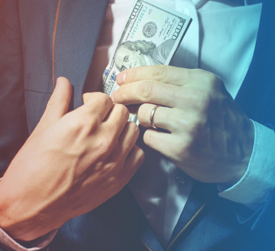 Мужчина прячет стодолларовые купюры в карман